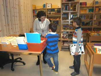 Eine Betreuerin verleiht in der Schulbibliothek Bücher an Kinder