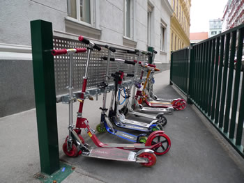 Grüne Scooterständer vor der Schule, voll mit abgestellten Scootern